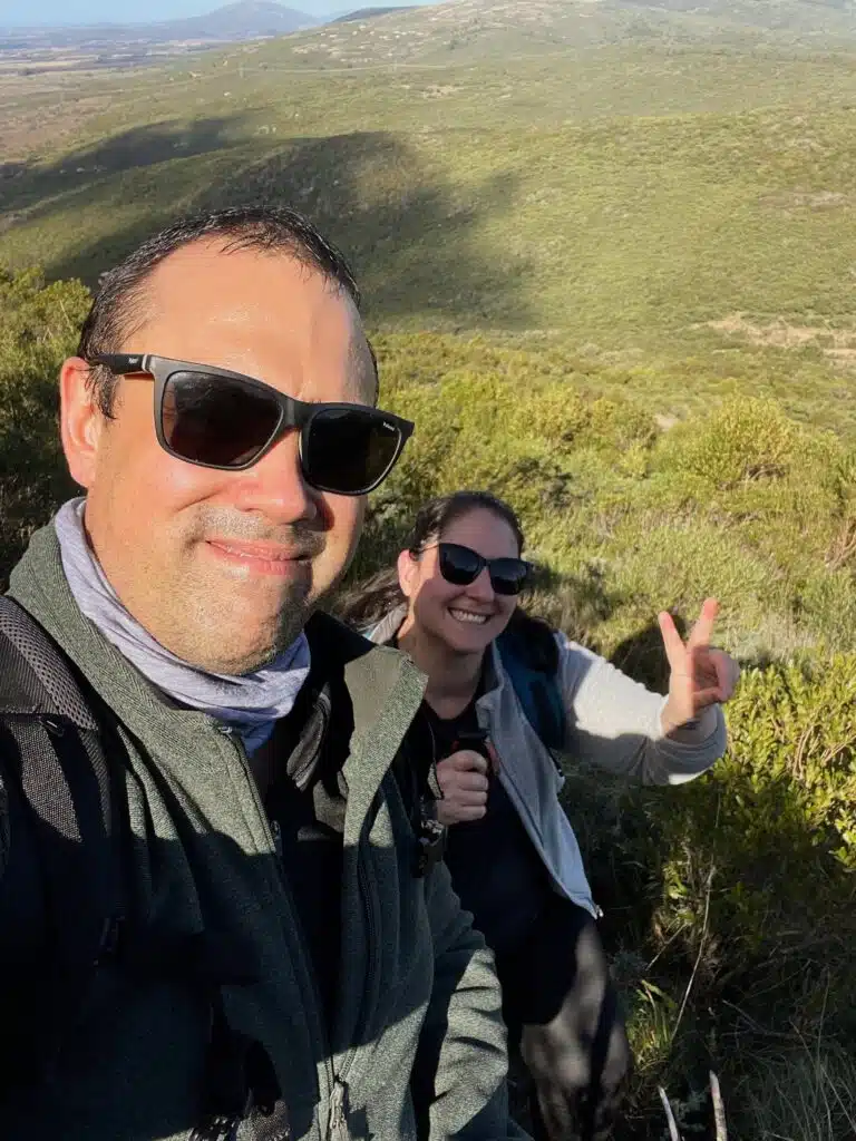 Cristhian de Mateando Rumbos y Vale sonriendo en una selfie, disfrutando de la naturaleza y el turismo sostenible en las sierras.