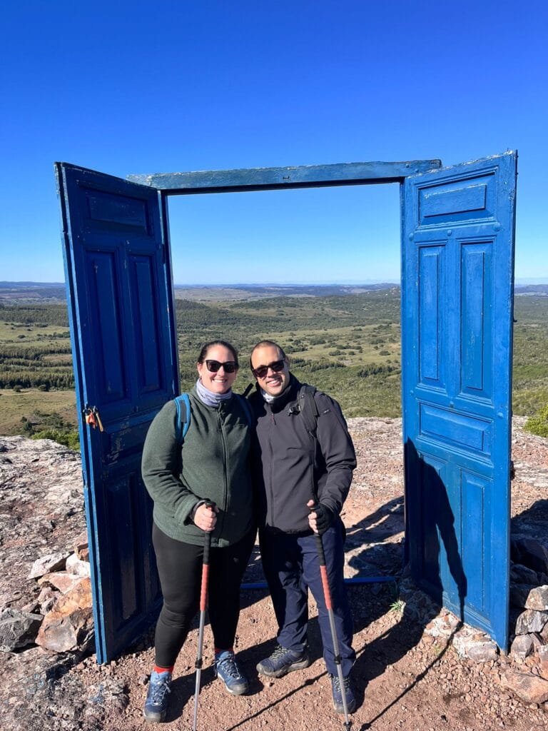 Pareja de viajeros posa en la famosa Puerta Azul del Cerro del Aguiar, en Lavalleja. El turismo sostenible te abre las puertas a experiencias auténticas como esta en Uruguay.